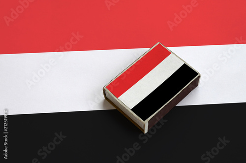 Yemen flag  is pictured on a matchbox that lies on a large flag photo