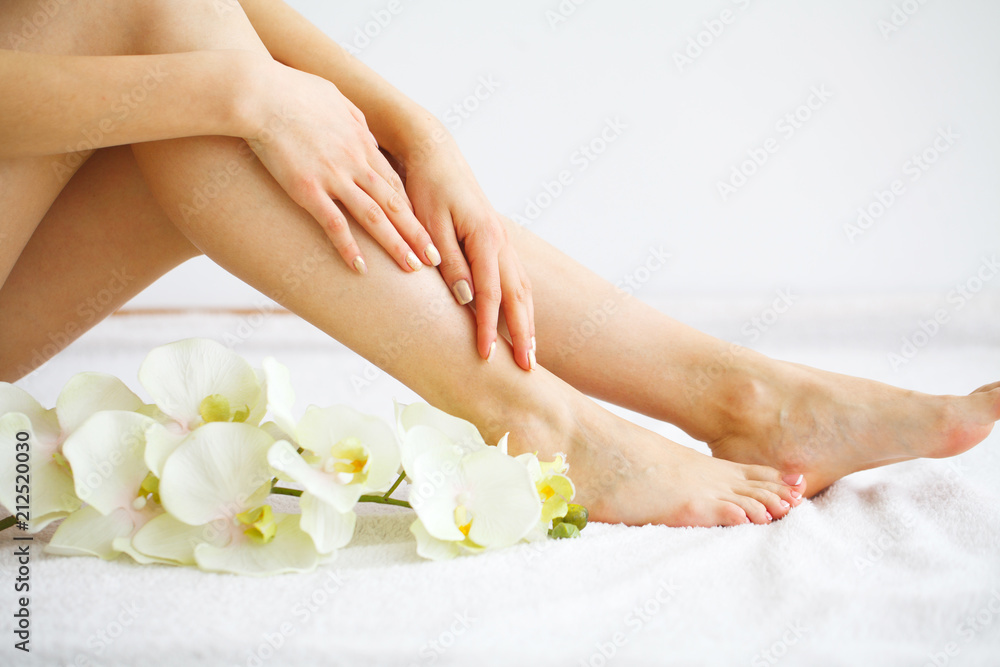 Fototapeta premium Spa. Woman massaging legs sitting on white background