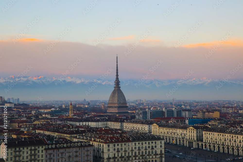 The Mole Antonelliana is seen in the middle. In the background there are the alps during a sunset in Turin, Piedmont, Italy.