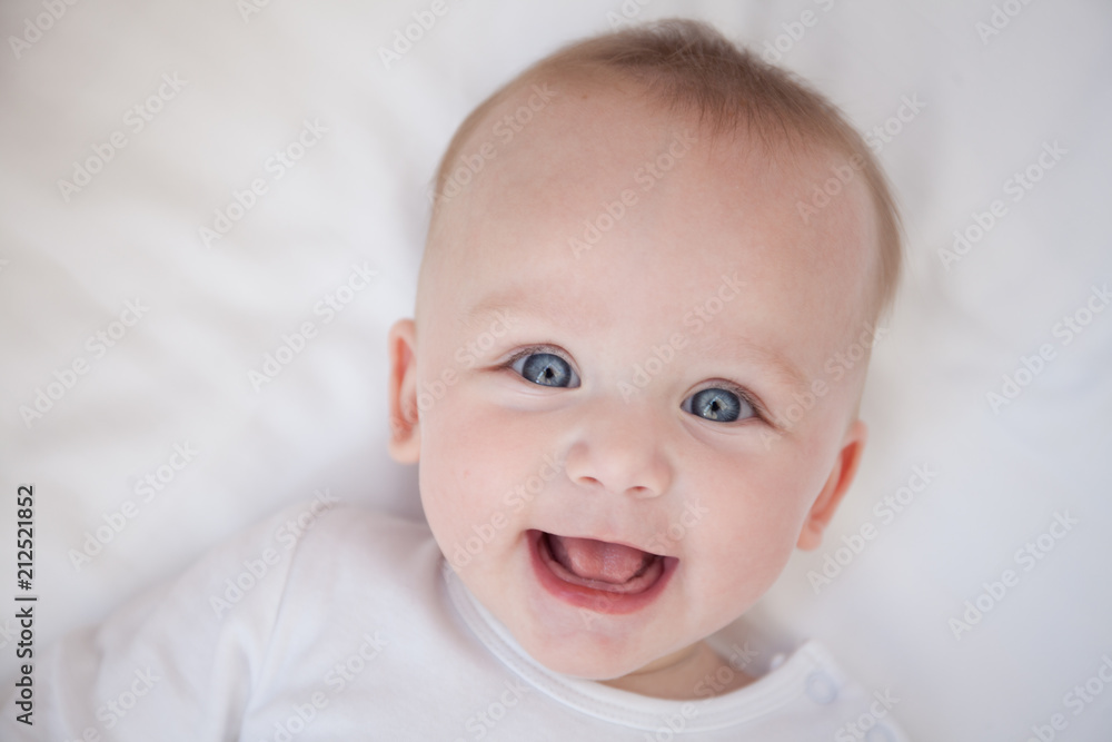 happy smiling child lies on his back on a white sheet