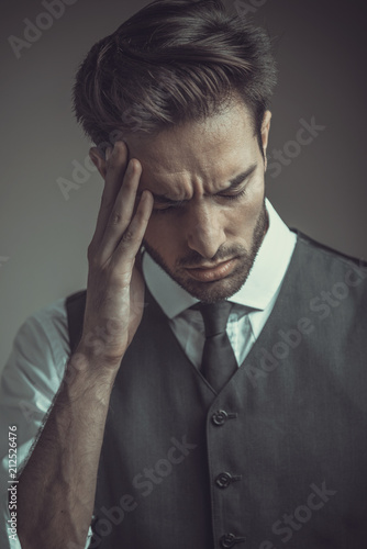 Tired businessman having a headache, dramatic studio portrait