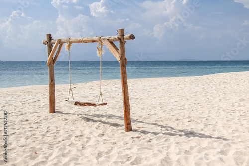 Wooden swing on the sand beach for summer holiday concept.