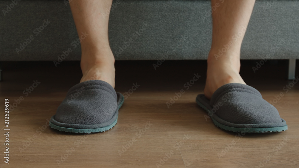 Legs of young adult man in a slippers - feet level