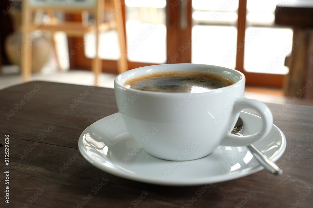 black coffee in the white cup on wooden table.