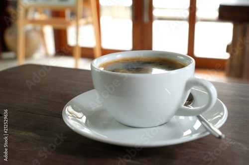 black coffee in the white cup on wooden table.