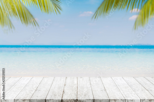 Empty wood table top and blurred Palm tree summer beach with blue sea and sky background. - can used for display or montage your products. © bunditinay
