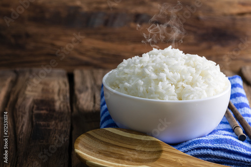 cooked rice in a white bowl with smoke on wooden floor