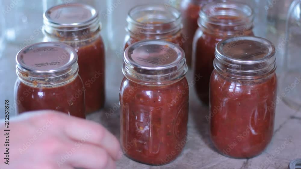 Lids are placed on class bottles or jars while doing some home canning. Lids are placed on class bottles or jars while doing some home canning.