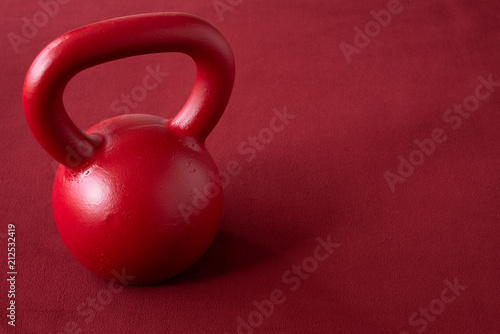 Red kettle bell on a red background
