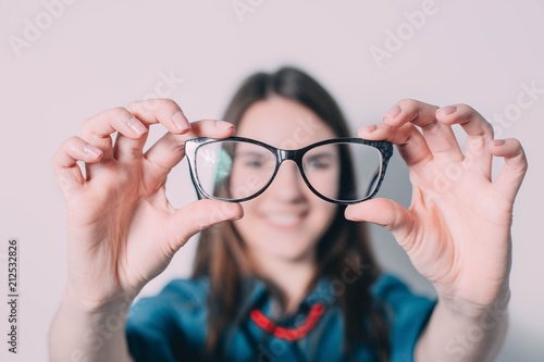 Glasses - optician showing eyewear. Closeup of glasses, with glasses and frame in focus. Woman optometrist on white background..