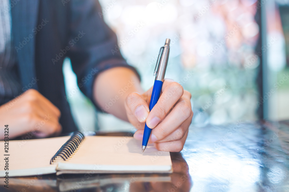 Business woman writing on a notebook.with a pen in the office