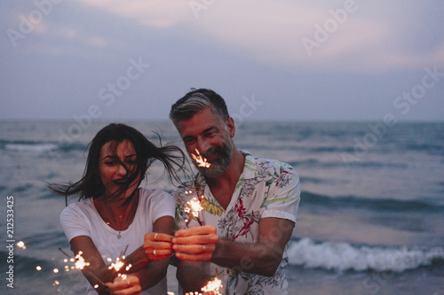 Photography Couple celebrating with sparklers at the beach