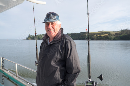 Portrait of a retired senior male tourist on a fishing charter boat at Mangonui, Far North District, Northland, New Zealand, NZ