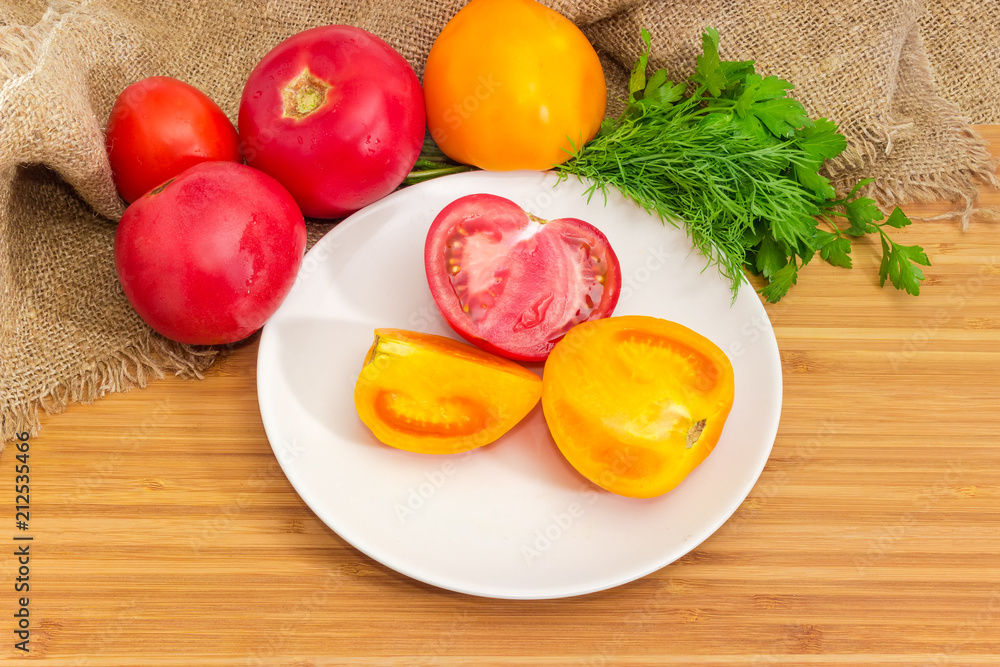 Cut and whole red and yellow tomatoes and greens Cut and whole red and yellow tomatoes and greens