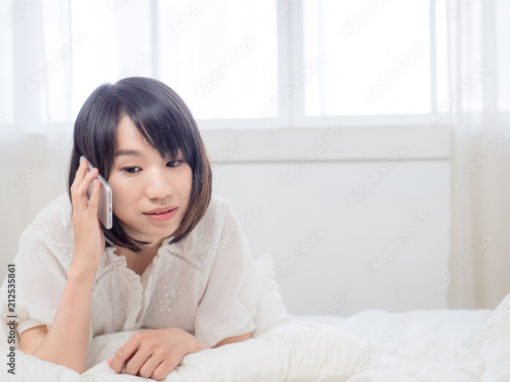 Beautiful young woman talking on the phone while in bed Beautiful young woman talking on the phone while in bed
