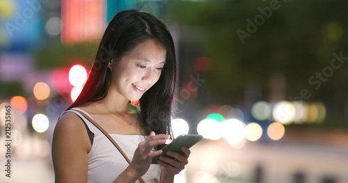 Woman use of app on cellphone in city at night