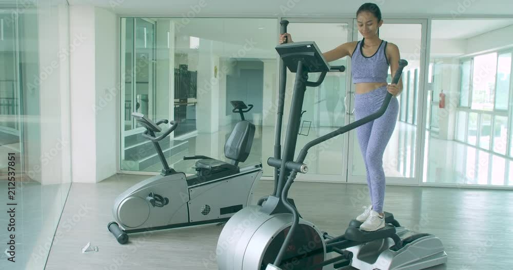 Attractive asian girl exercising cardio on the elliptical machine in the gym. Attractive asian girl exercising cardio on the elliptical machine in the gym.