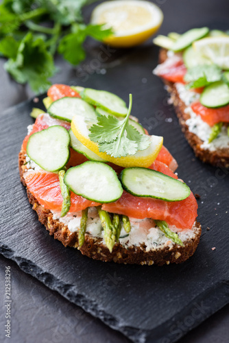 Sandwich with salmon, cream cheese and cucumber on slate background, closeup view, selective focus