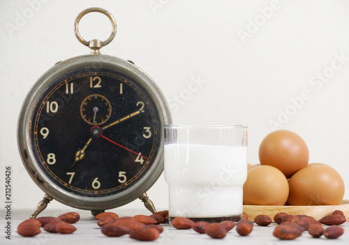 Milk and almond with clock and egg on background