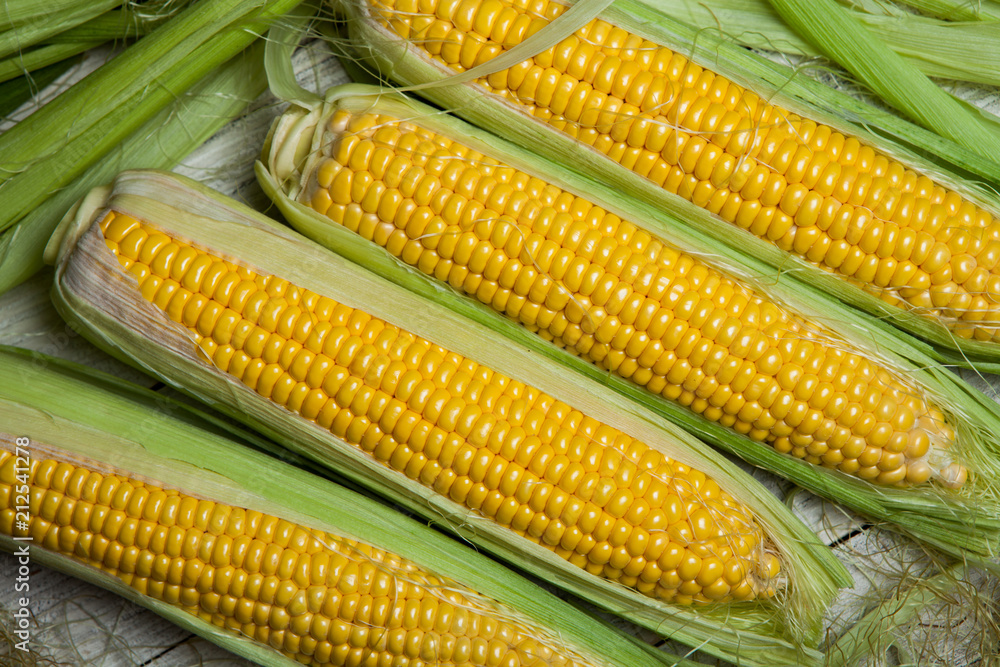 Fresh corn on cobs on rustic wooden table, close up. Sweet corn ears background Fresh corn on cobs on rustic wooden table, close up. Sweet corn ears background