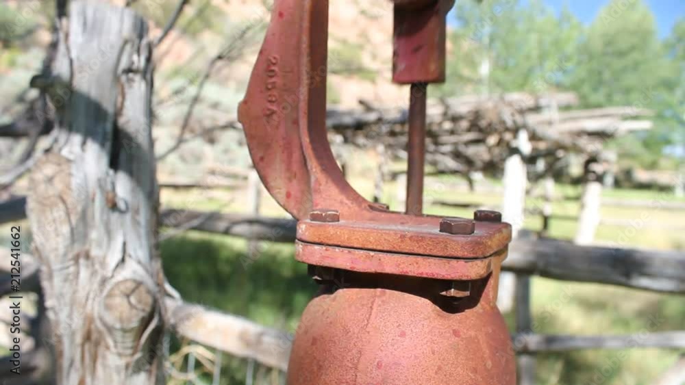 Close shot of a faded red water pump in a old pasture. Close shot of a faded red water pump in a old pasture.