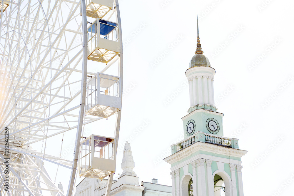Tourist attractions. The photo of a big observation wheel and a beautiful ancient bell tower standing in the city center