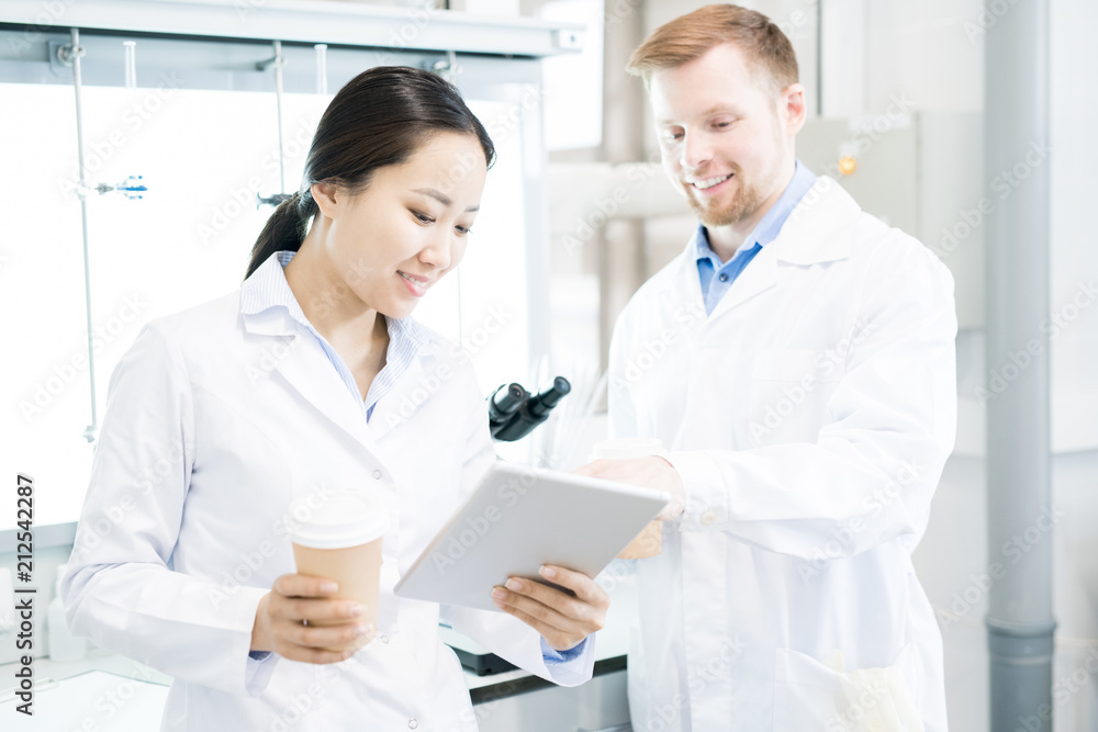 Waist up portrait of two modern young scientists wearing lab coats taking break from working in medical laboratory Waist up portrait of two modern young scientists wearing lab coats taking break from working in medical laboratory