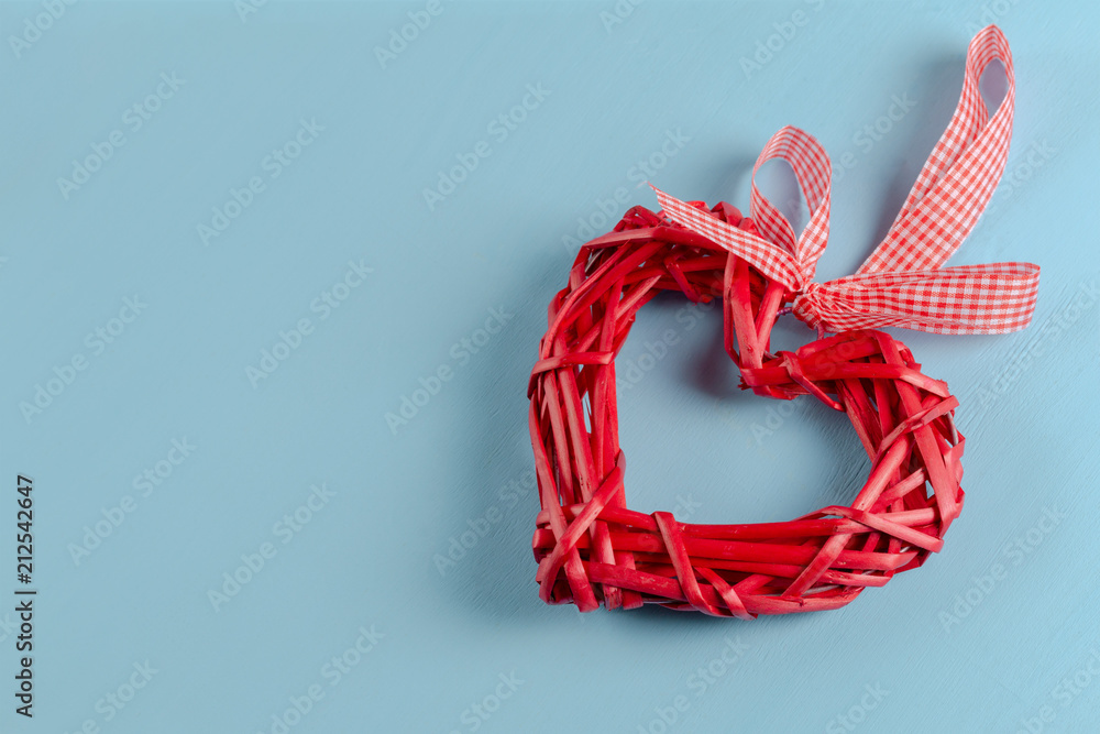 Red woven straw heart on blue background. Symbol of love or health Red woven straw heart on blue background. Symbol of love or health