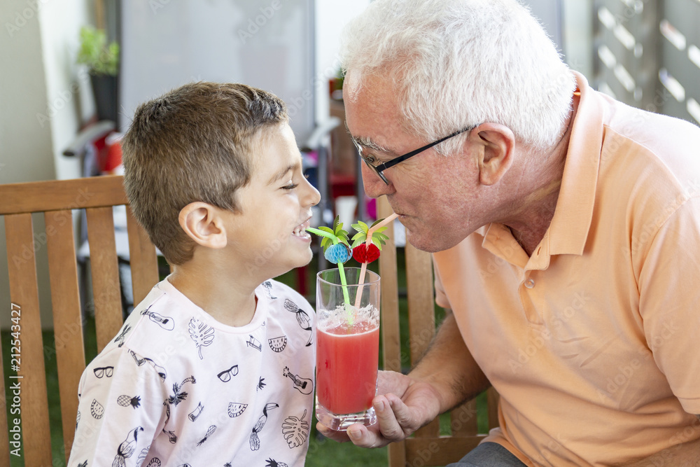 Grandfather and grandson drinking watermelon juice at the same time Grandfather and grandson drinking watermelon juice at the same time
