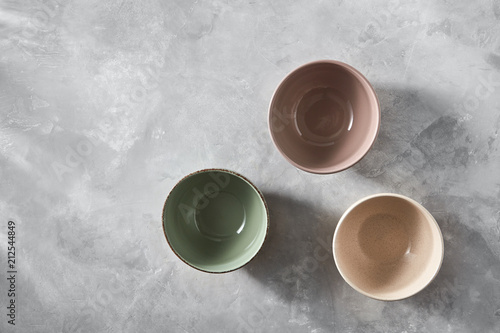 Three colorful porcelain bowls isolated on stone gray background, flat lay