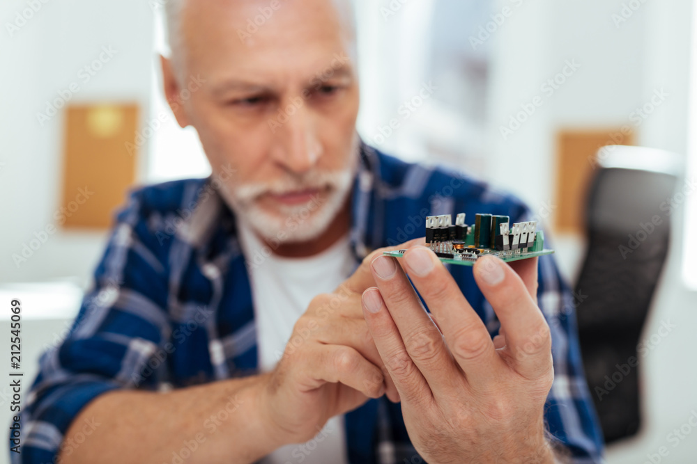 Sophisticated technology. Selective focus of a microscheme being in hands of a smart positive engineer Sophisticated technology. Selective focus of a microscheme being in hands of a smart positive engineer