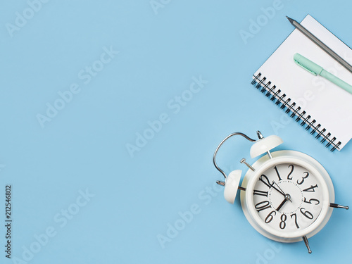 Alarm and notepad on color background