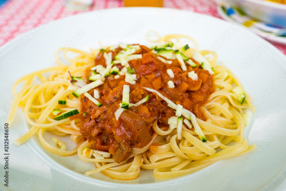 Italian linguine with vegan bolognese sauce based on soy beans and vegetables served on a white plate