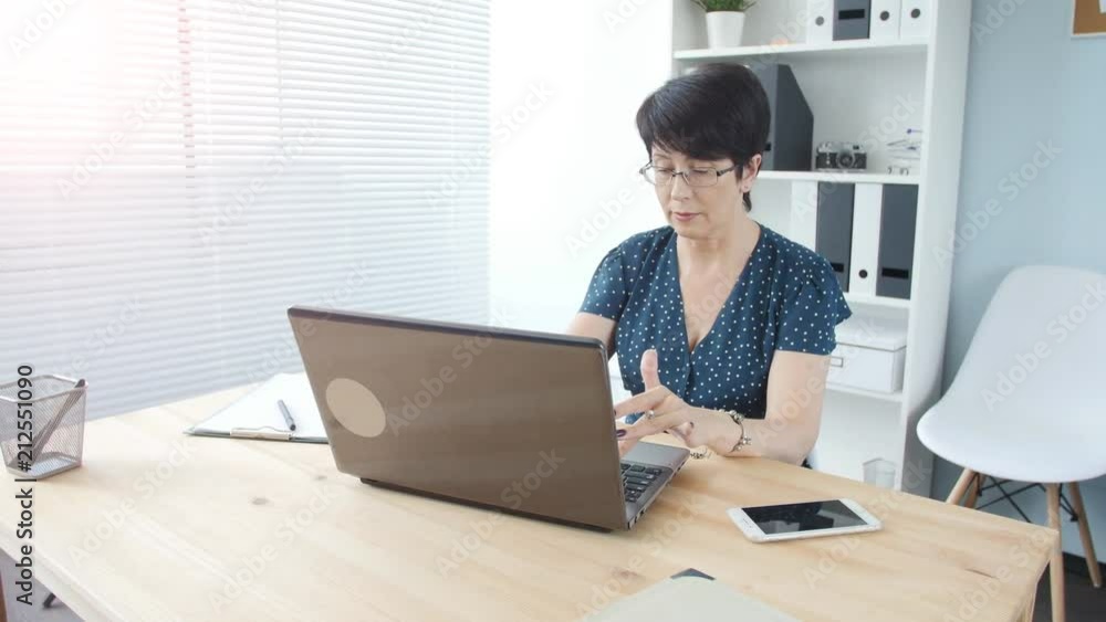 An attractive middle aged businesswoman with a laptop in the office An attractive middle aged businesswoman with a laptop in the office