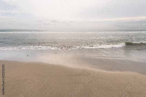 sea wave reach sandy beach under cloudy sky