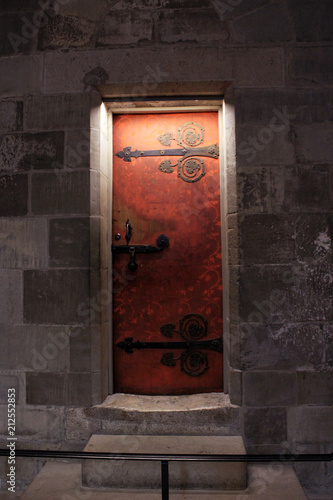 Old red magnificent door with stone walls and a little light