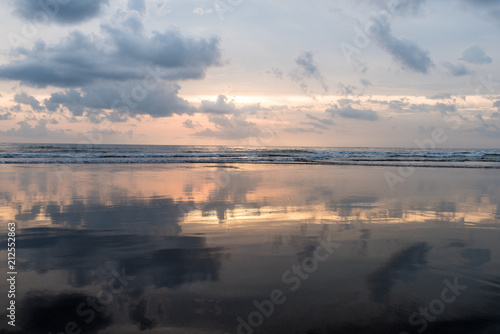 sunset at wet smooth sandy beach