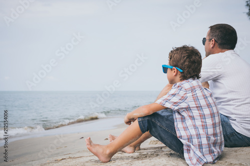 Portrait of young sad little boy and father sitting outdoors at the day time. © altanaka