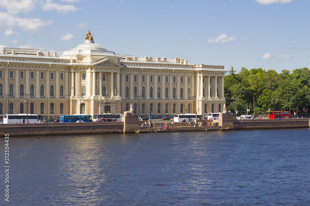 A view of the historical building of the Academy of Arts and the University Embankment on the Neva River on a summer sunny day in St. Petersburg in Russia.