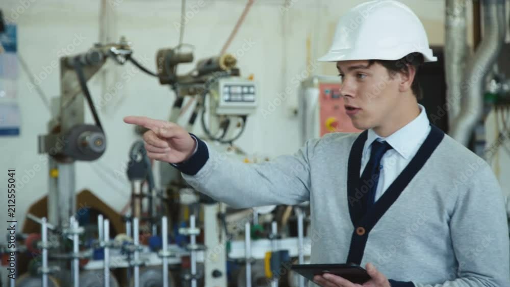 Young engineer in helmet works with table on the factory 4K Young engineer in helmet works with table on the factory 4K