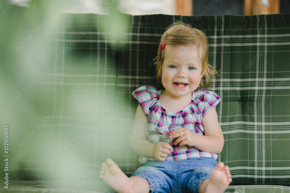 The small child sits on the sofa in room The small child sits on the sofa in room