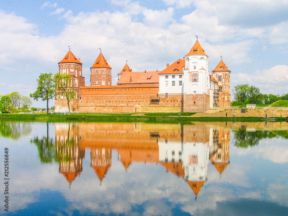 Mir, Belarus. Castle Complex Mir reflected in lake On Sunny Day with blue sky Background. Old medieval Towers and walls of traditional fort from unesco world heritage list