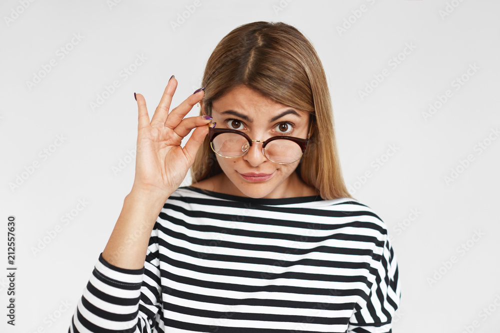 People, style, fashion, eyewear and optics concept. Stern beautiful young  lady wearing striped top, lowering her stylish eyeglasses in black frame  and straring at camera with scrutinizing look Stock Photo | Adobe