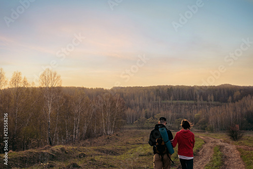 Two travelers leave for the sunset in the backgrounds. Tourism.