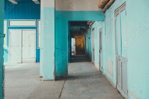 A corridor In a rickety building. going into the distance, blue weathered walls.