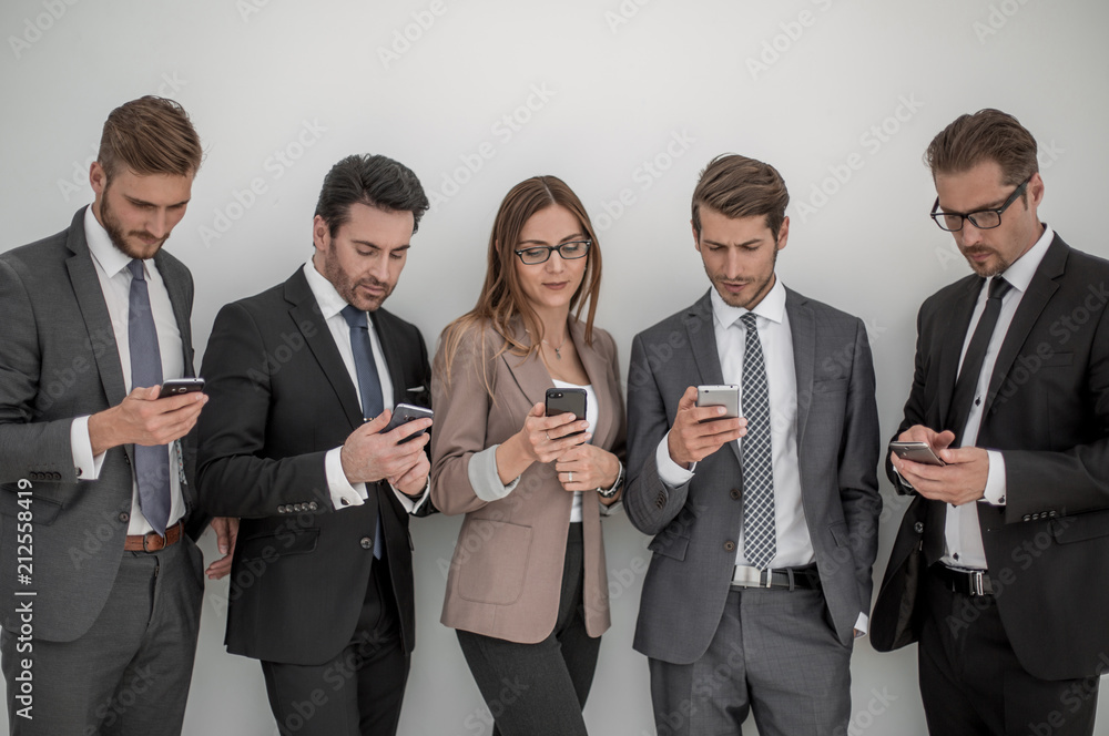 group of business people looking at the screens of their smartphones group of business people looking at the screens of their smartphones