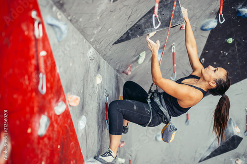 Sporty successful business woman being busy at her hobby-bouldering. Well equipped woman training in a colorful climbing gym, preparing to summer mountain ascend photo