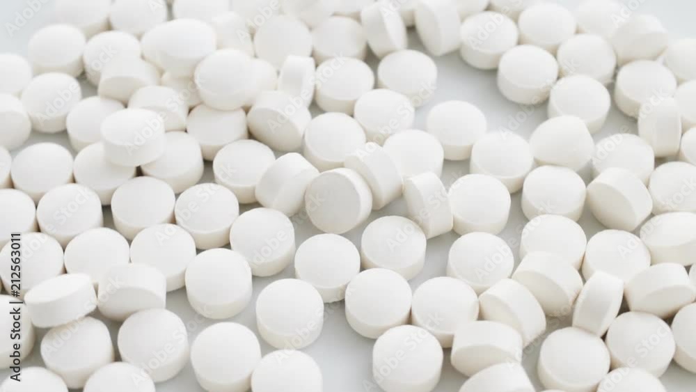 White tablets, pills slow rotation, closeup, white background. Concept of pharmaceuticals; meds, drugs, pharmacology, materia medica. Closeup. White tablets, pills slow rotation, closeup, white background. Concept of pharmaceuticals; meds, drugs, pharmacology, materia medica. Closeup.