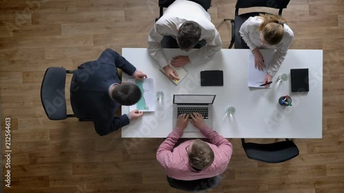 Boss coming in and team of four people starting meeting, topshot, businessmen planning new project in modern office