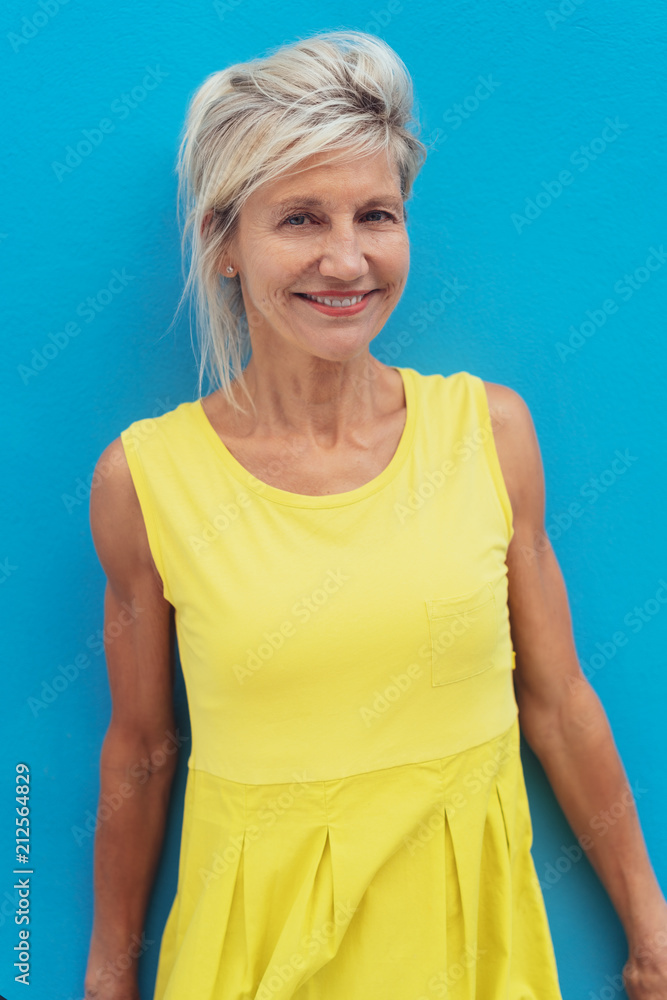 Happy mature blonde woman wearing yellow dress foto de Stock | Adobe Stock